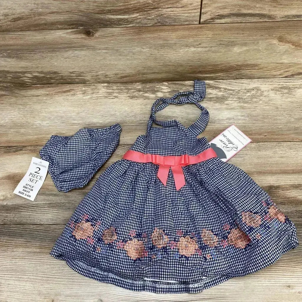 Flat lay of navy gingham baby dress and matching bloomers 3-6M showing pink ribbon waist and floral embroidery on wood floor