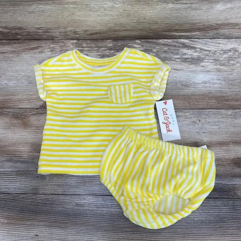 Top-down view of yellow-and-white striped terry baby shirt and matching shorts showcasing chest pocket and elastic waist on wood background
