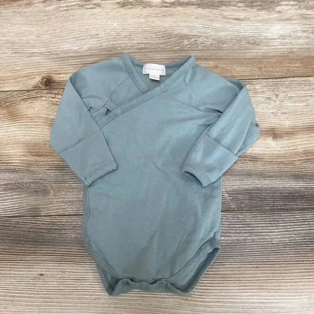 Flat lay of sage kimono bodysuit size 6-9 months with long sleeves, side wrap snaps and three bottom snaps on wood background