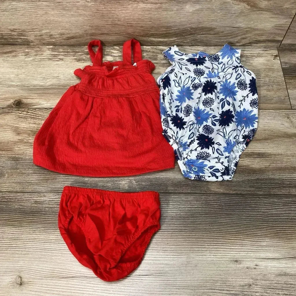Flat lay of 3-piece baby romper set showing red sleeveless dress, red bloomers, and white-blue floral romper on wood floor