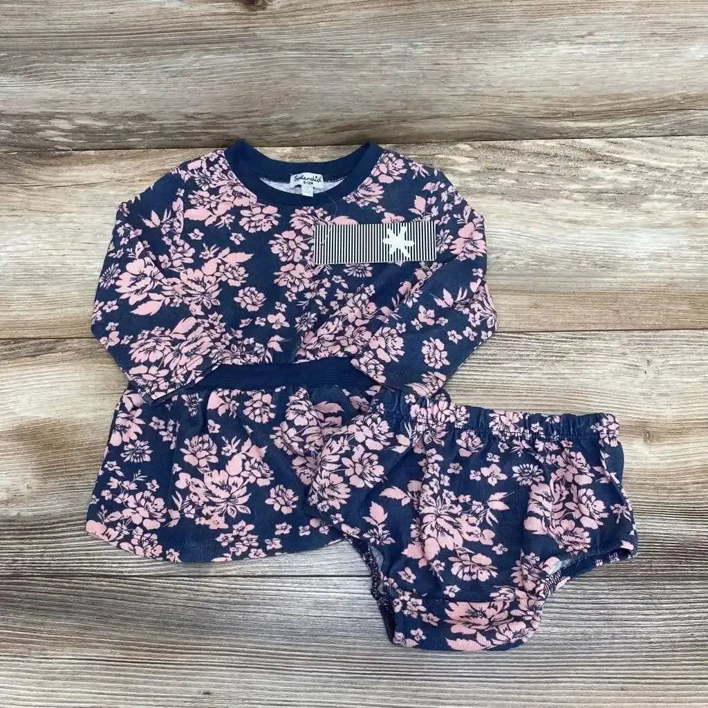 Flat lay of Splendid long-sleeve navy baby dress with pink floral print and matching bloomers on wooden background
