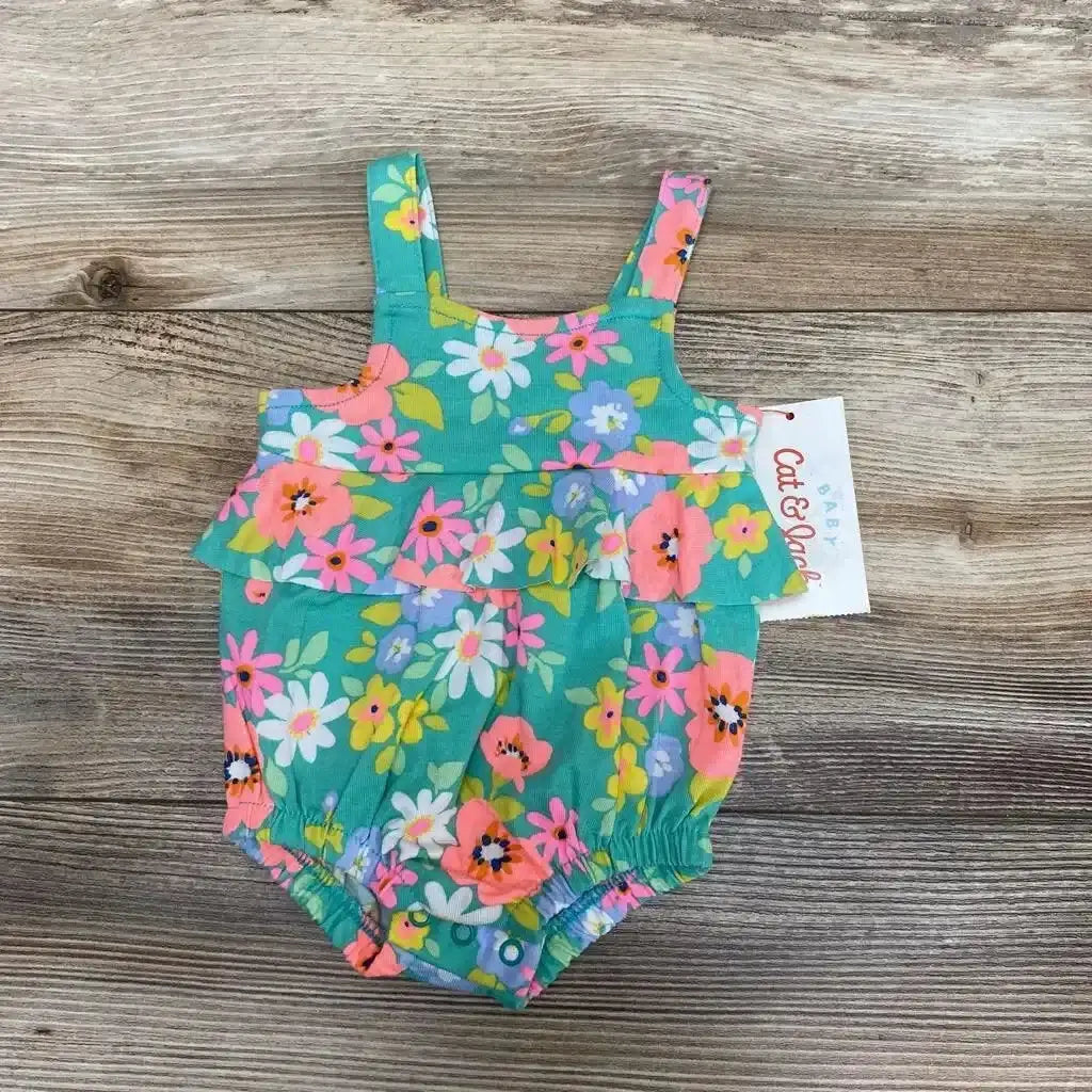 Flat lay of Cat & Jack newborn floral sunsuit showing ruffled front and elastic legs in green floral print on wood surface