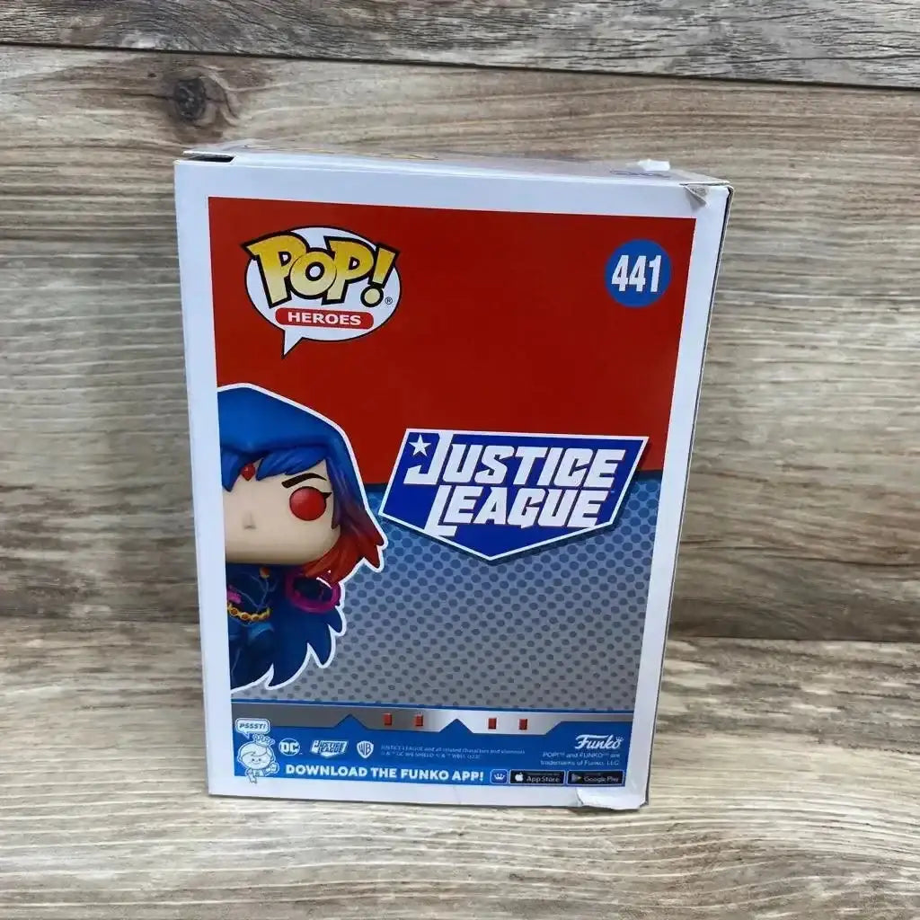 Front view of boxed Funko Pop Justice League Raven (#441) showing character artwork and slight top-right box damage on wood background