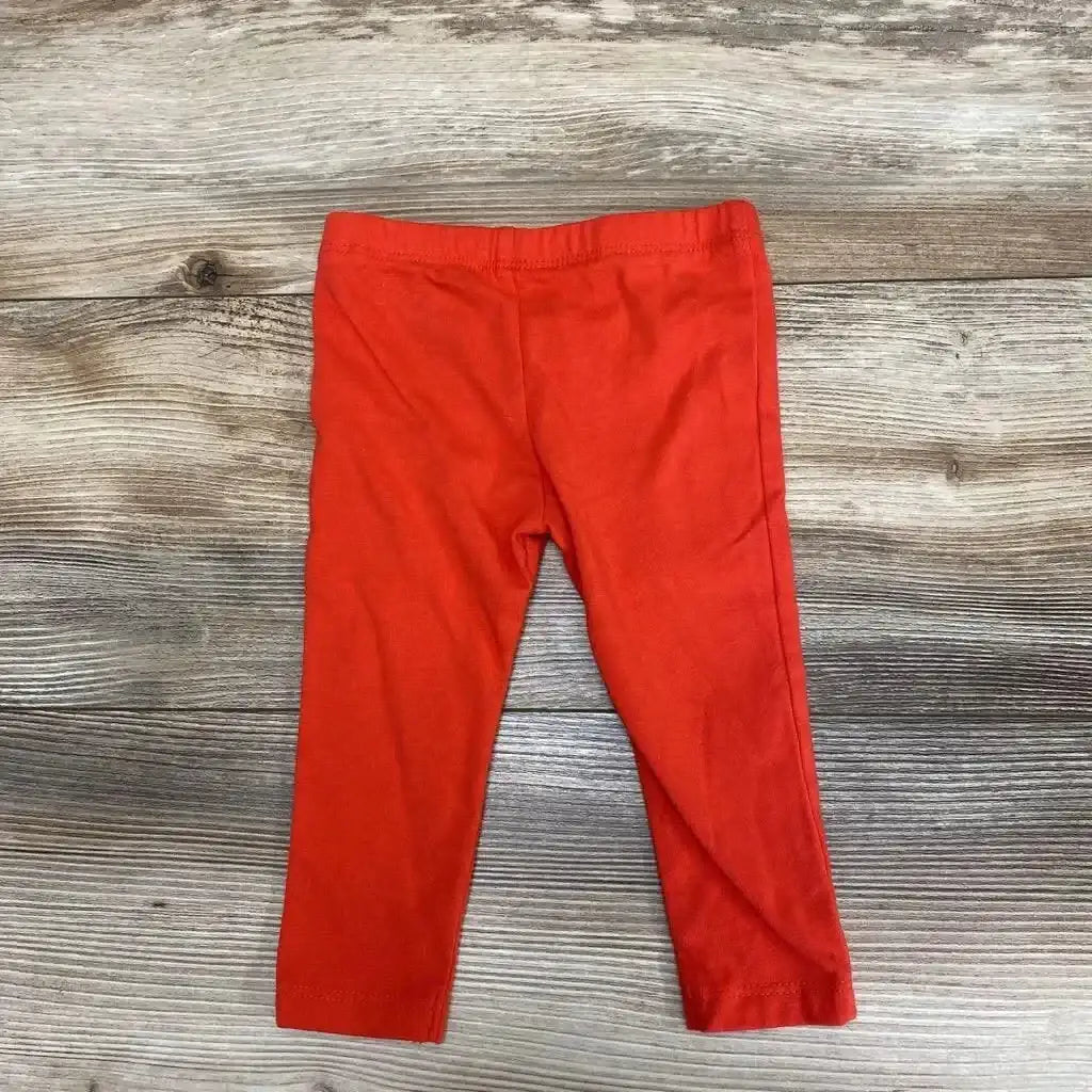 Flat lay of Cat and Jack leggings sz 6-9m showcasing solid red orange fabric with elastic waistband on wood plank floor