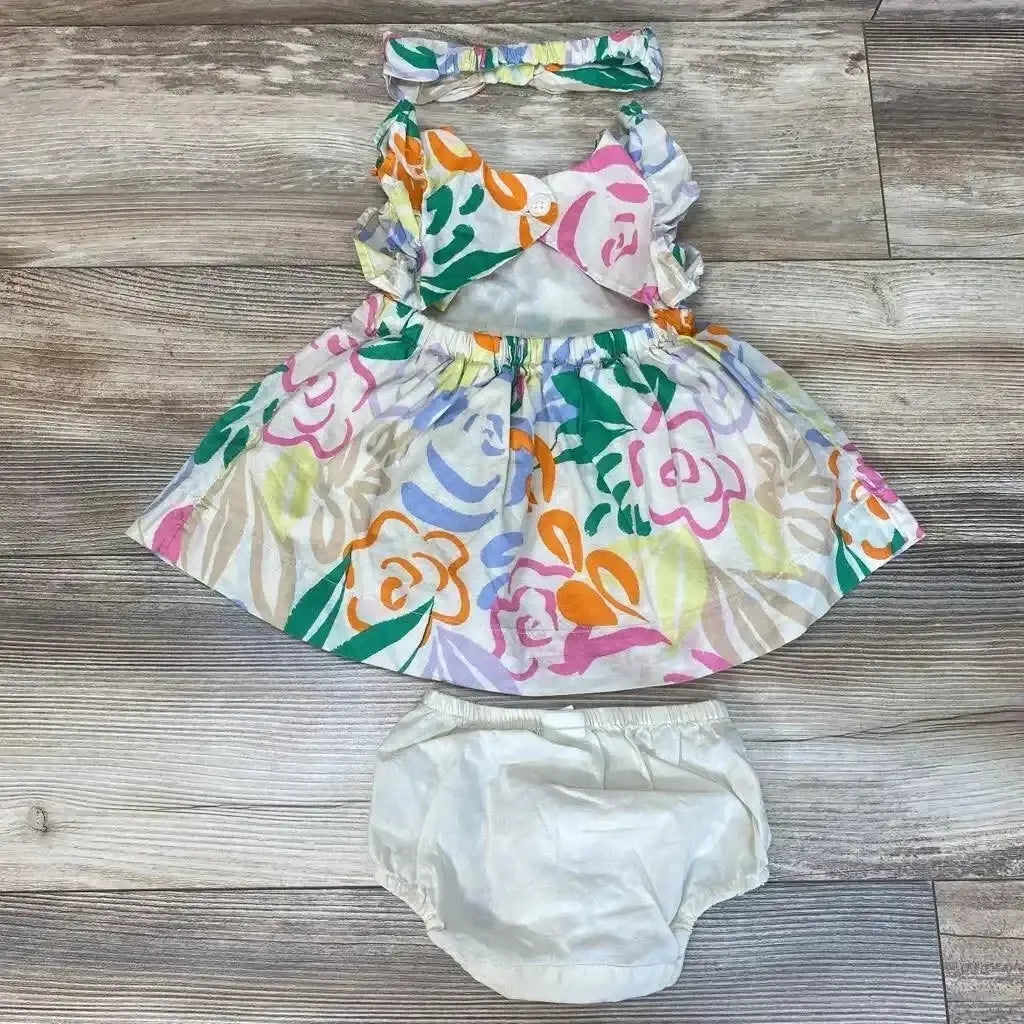 Front flat lay of BabyGap 3-piece tropical floral dress with ruffled straps, matching headband and white bloomers on wood