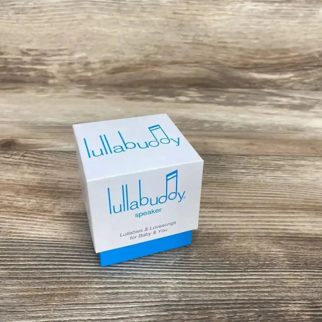 Three-quarter view of Lullabuddy Portable Speaker in original white and blue retail box on wood plank floor