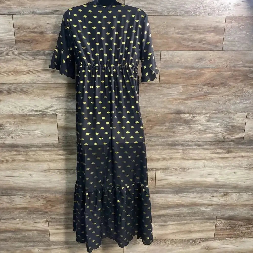 Front view of black maternity maxi dress with yellow oval polka-dot pattern, elastic empire waist and ruffle hem against wood plank background