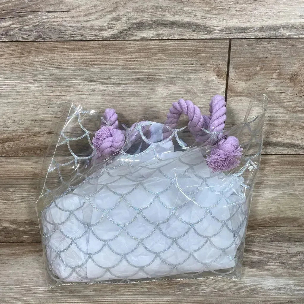 Front view of clear mermaid purse with silver scale print and lavender rope handles showing included white inner pouch on wood background