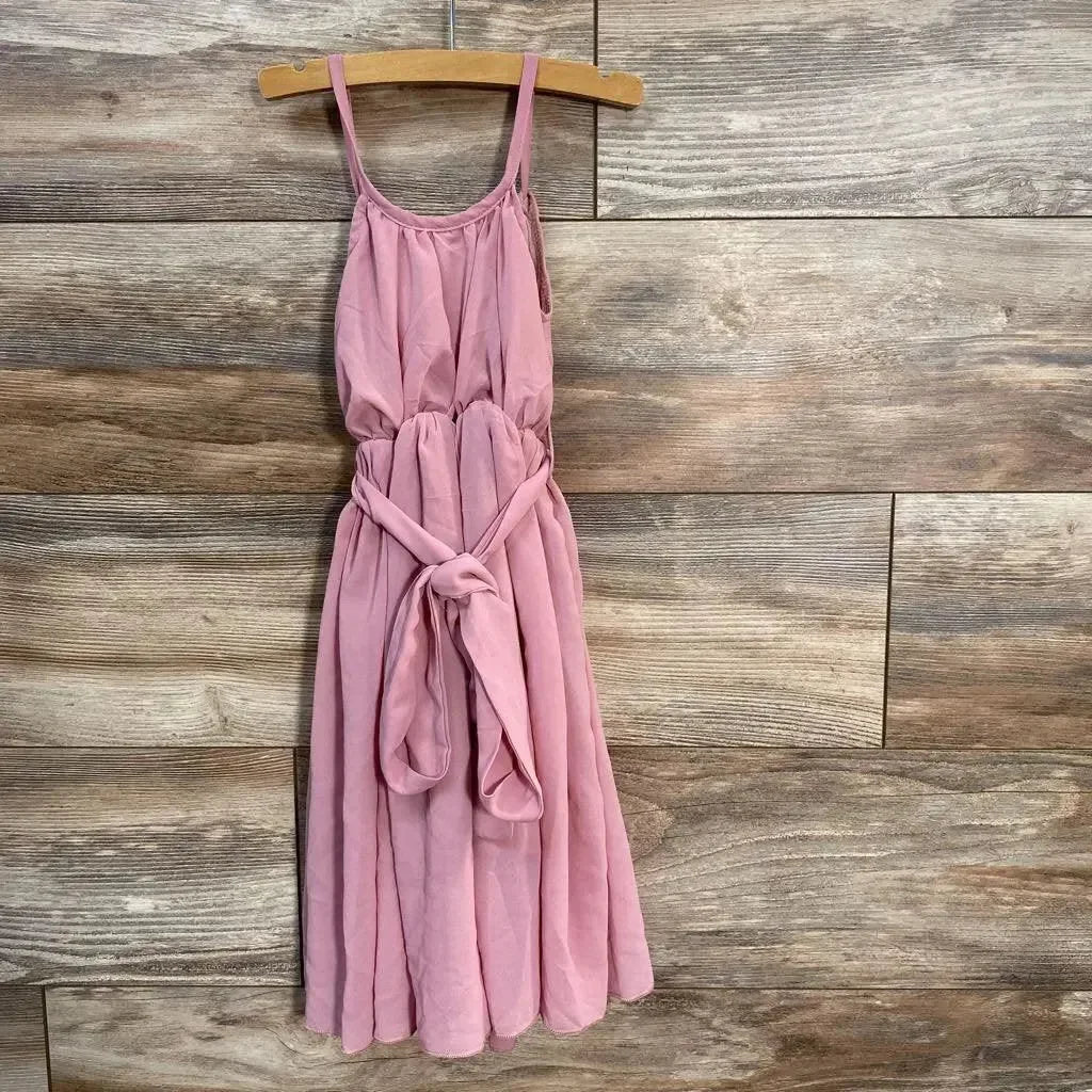 Front view of Bailey's Blossoms pink sleeveless baby dress (9-12 months) showcasing tied waist sash and spaghetti straps on wood-plank background