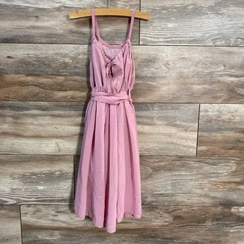 Front view of pink sleeveless dress, 9-12m, with spaghetti straps, ruffled bodice and tied waist on wood background