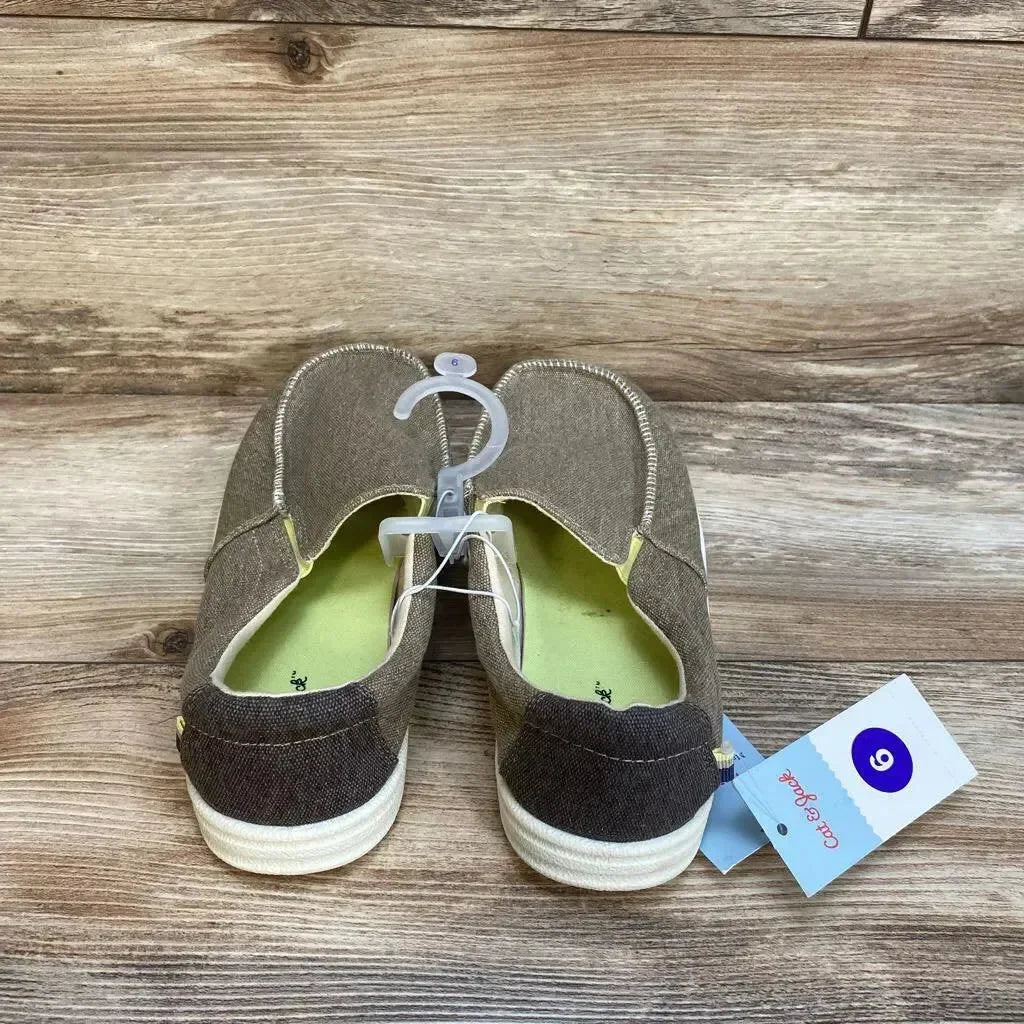 Rear view of Bergen slip-on sneakers, youth size 6, beige canvas with white rubber soles and green insoles on wood background