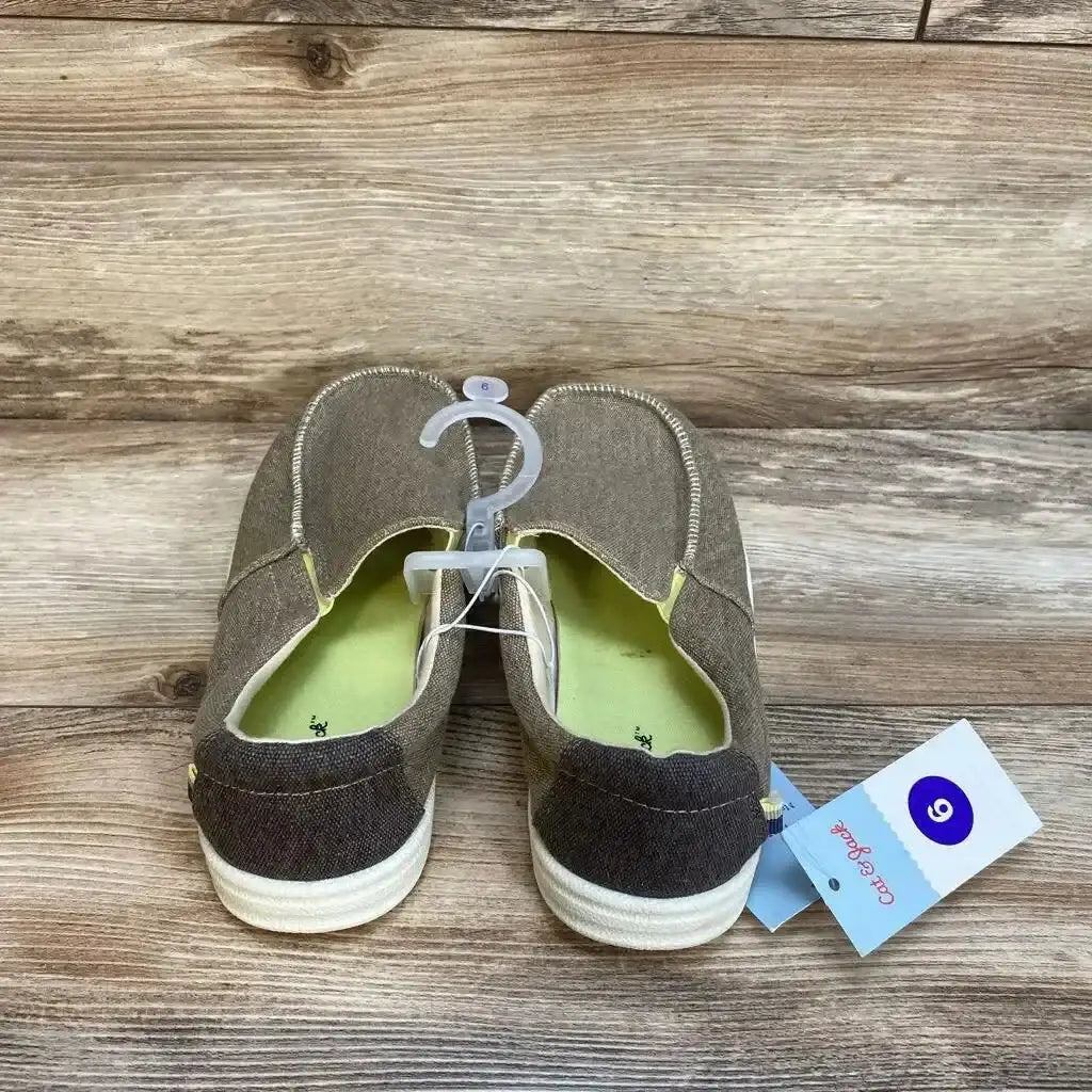 Rear view of Bergen slip-on sneakers, youth size 6, beige canvas with white rubber soles and green insoles on wood background