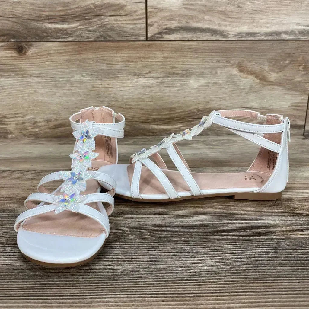 Side-front view of white Loganberry gladiator sandals, size 4Y, with iridescent flower T-strap and back zipper on wood