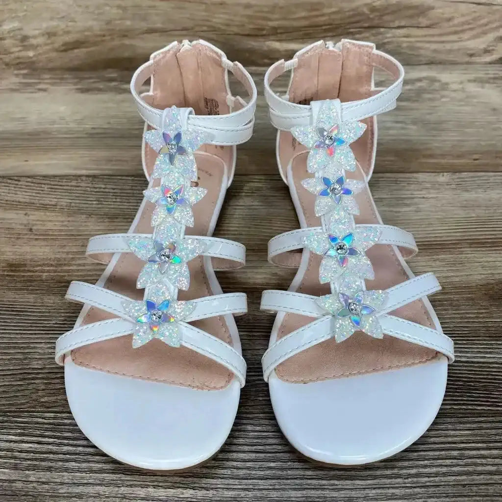 Top view of white New SO Loganberry toddler gladiator sandals with sparkly flower embellishments on wood