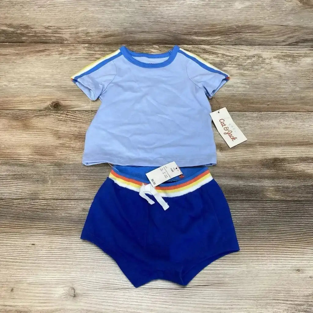 Flat lay of Cat & Jack 2-piece: light blue tee with rainbow sleeve trim and royal blue shorts with rainbow waistband on wood