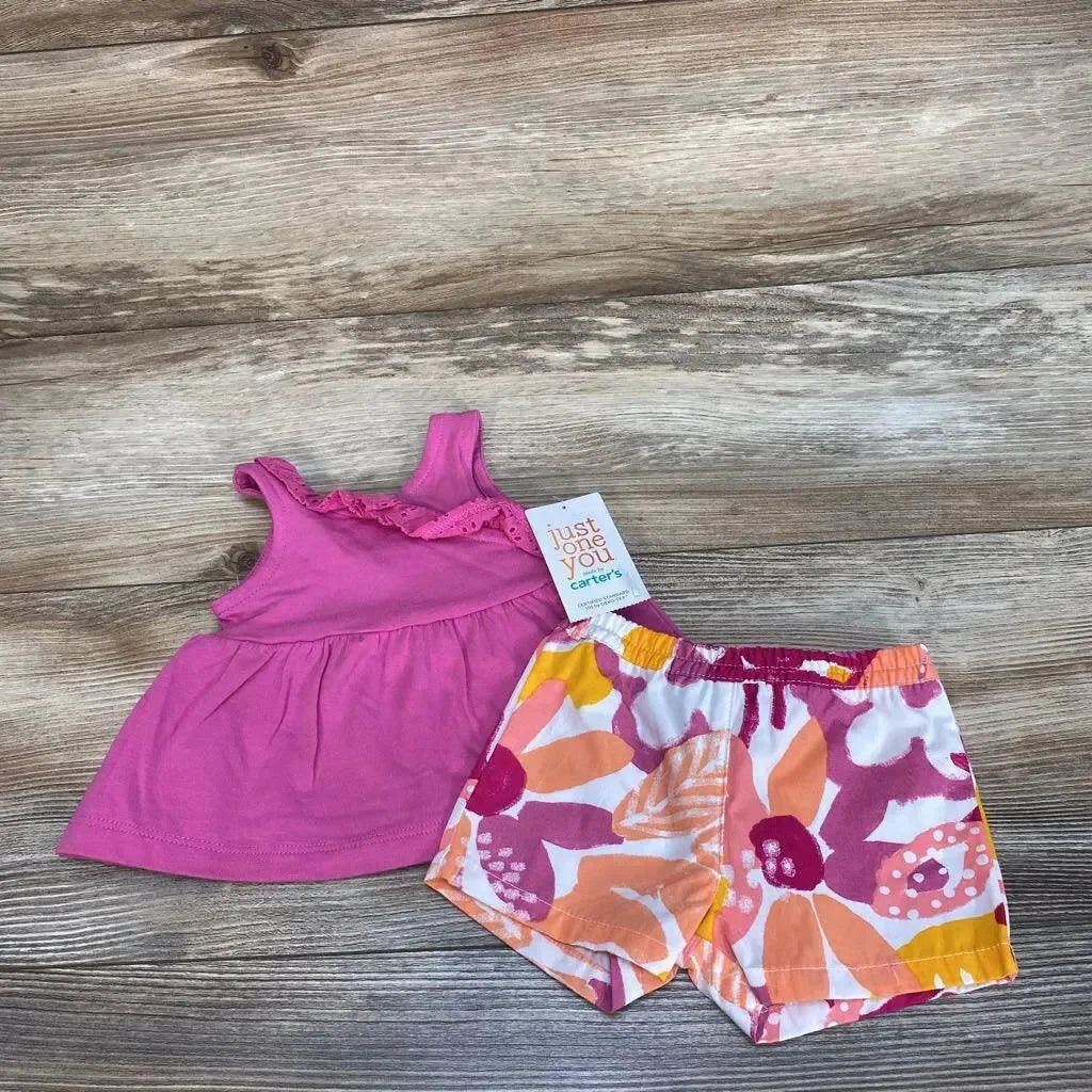 Front view of pink baby tank top and orange-pink floral shorts showcasing ruffle detail and elastic waist, laid flat on wood background