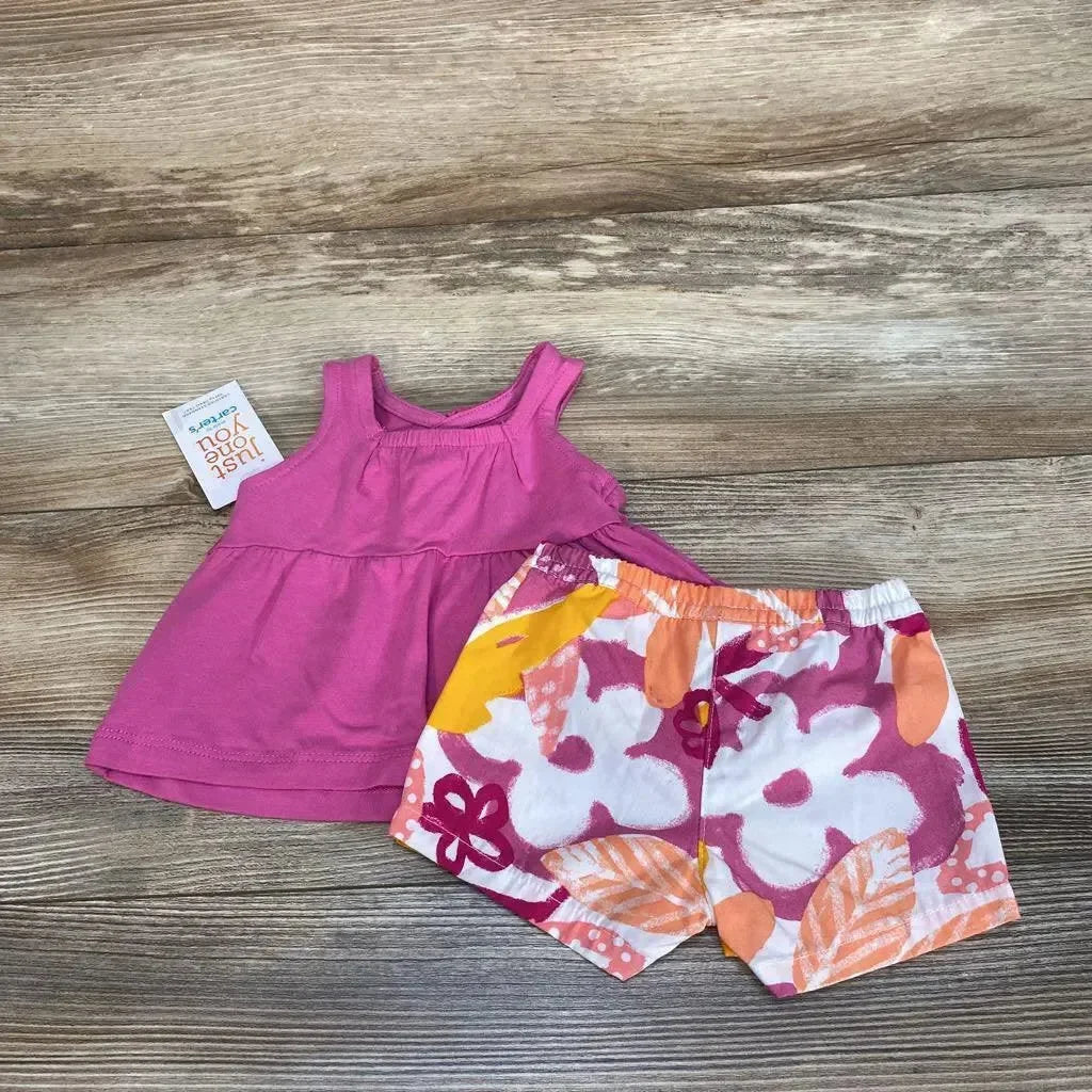 Flat lay of purple baby tank top and floral pink, orange and white shorts showcasing elastic waistband and layered hem on wood background