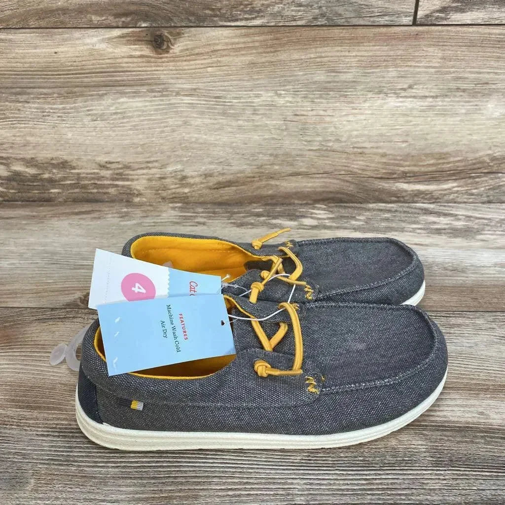 Side view of Cat & Jack Briar slip-on sneakers showing grey chambray fabric, yellow lining and laces on a wood background