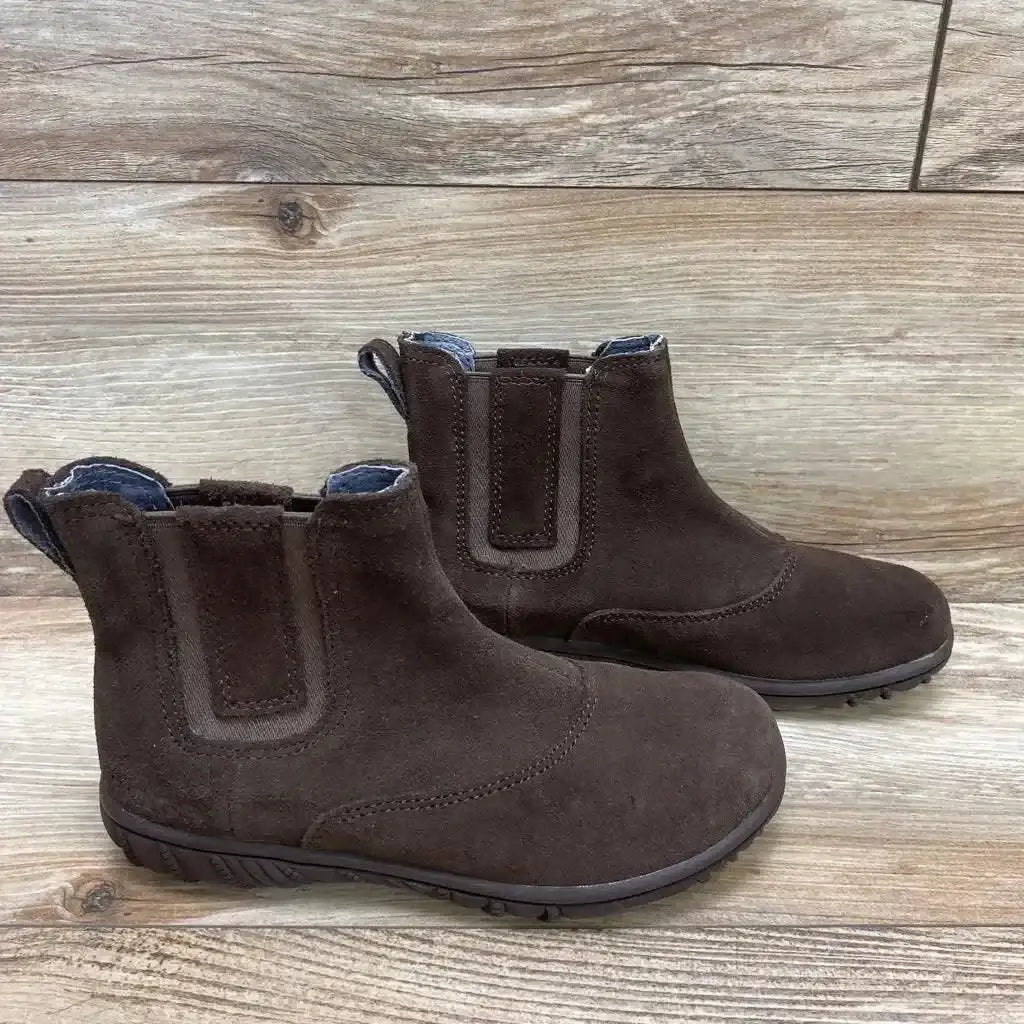 Side view of brown toddler Bogs Wall Ball Chelsea boots showing elastic side panels and pull tabs on a wood floor background