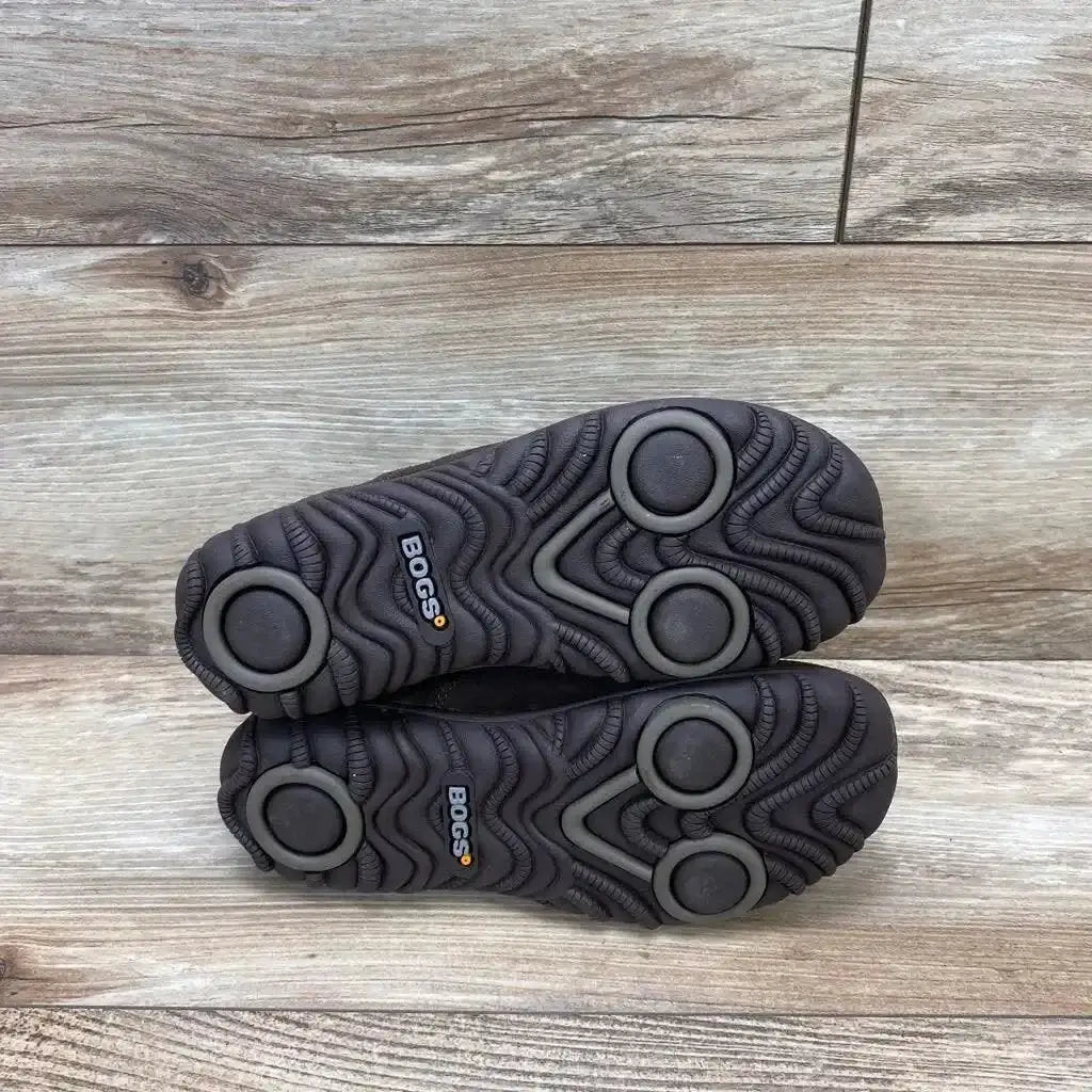 Soles view of toddler Bogs Chelsea boots showing circular tread and BOGS logo on brown rubber soles on light wood background