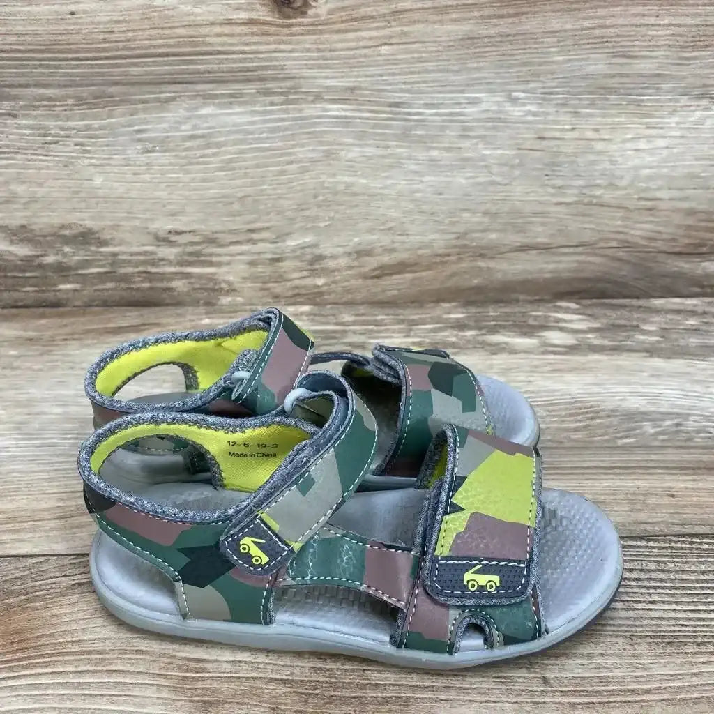 Side view of See Kai Run Billie toddler sandals, green camo, size 12C, two Velcro straps and cushioned footbed on wood
