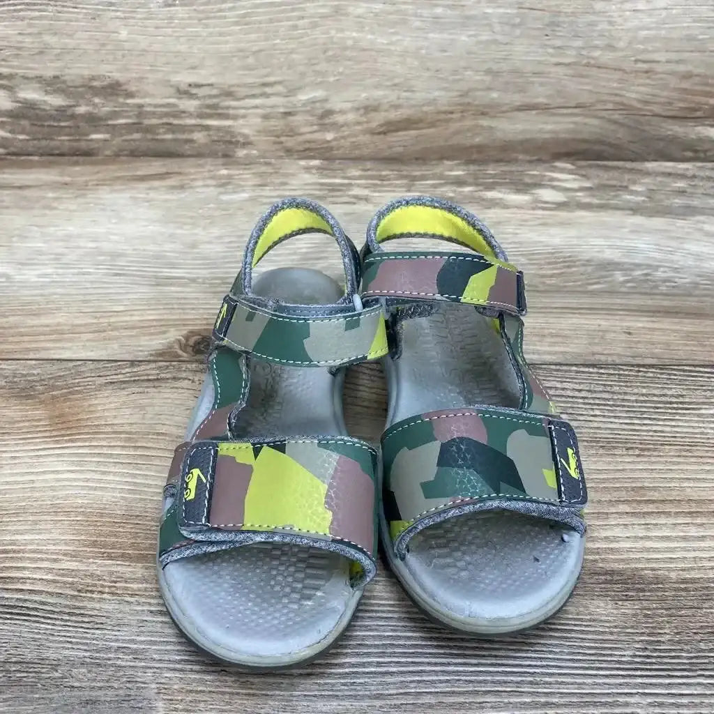 Top-down view of green camo See Kai Run toddler sandals size 12c with Velcro straps on wooden background