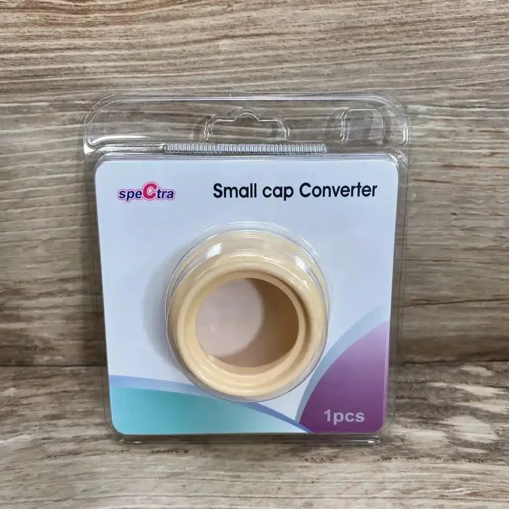 Front view of Spectra small cap converter, beige adapter in clear blister pack with label Small cap Converter on wood