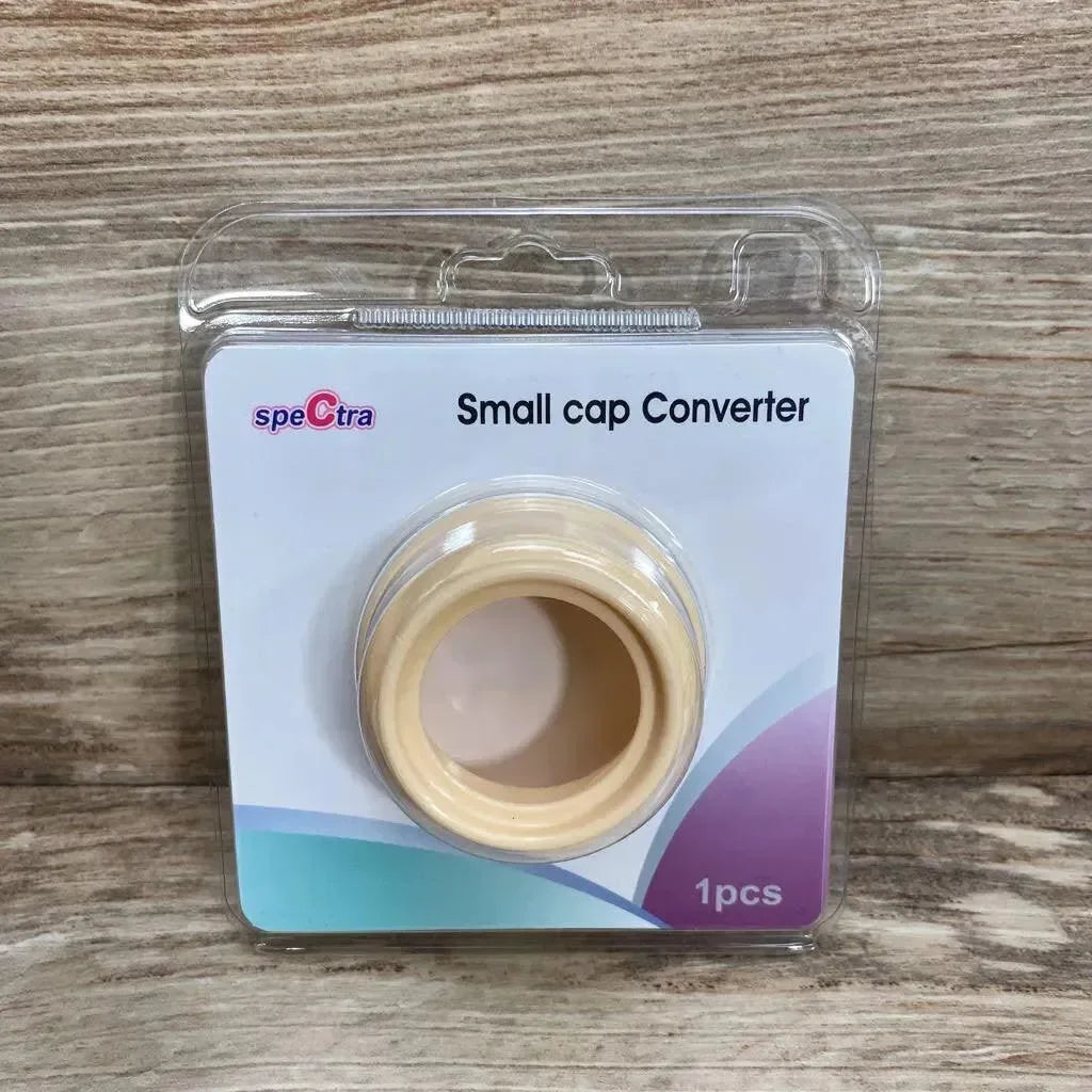 Front view of Spectra small cap converter, beige adapter in clear blister pack with label Small cap Converter on wood
