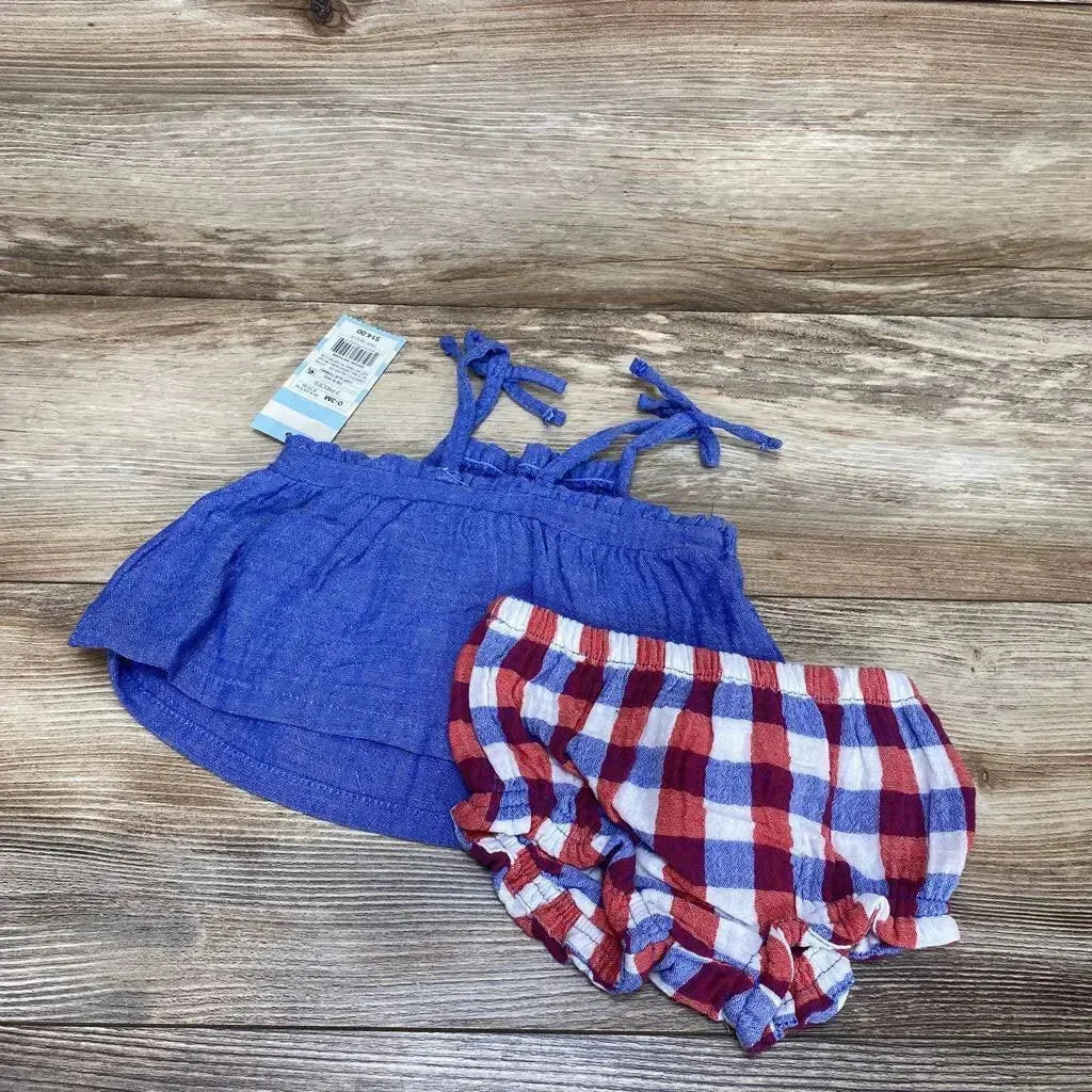 Flat lay of blue smocked baby top with tie shoulder straps and red white and blue plaid bloomers, size 0-3 months, on wood background