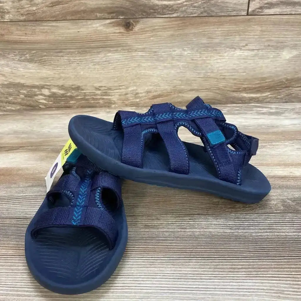 Side view of navy All in Motion Lumi kids' ankle-strap sandals with three straps and textured footbed on wooden surface