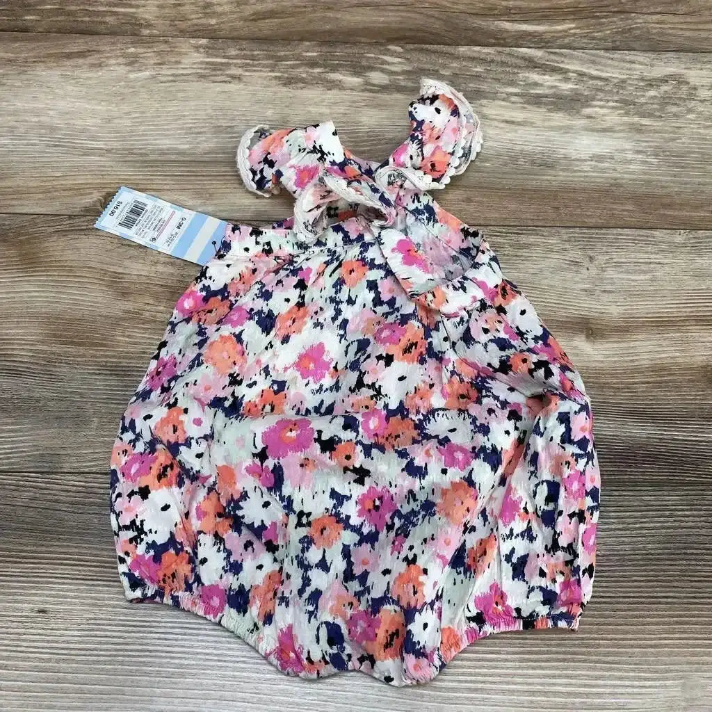 Top view of Cat and Jack romper in pink and coral floral print with flutter sleeves trimmed in lace and a back tie on wood surface