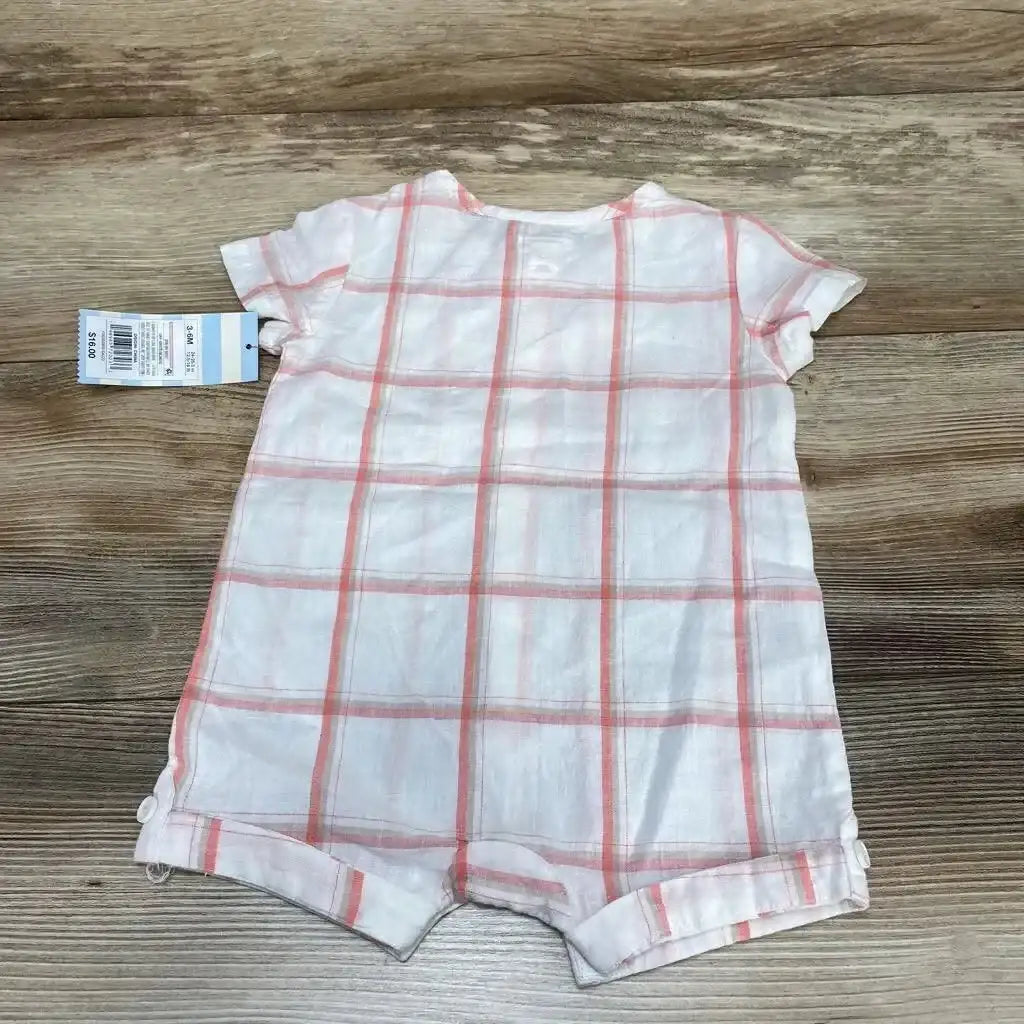Flat-lay back view of white baby shortie romper with pink plaid, short sleeves, rolled leg cuffs and tag on wood background