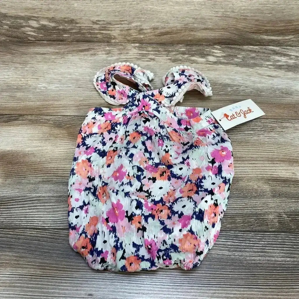 Top down newborn Cat and Jack pink floral romper, flutter sleeves and elastic leg openings, brand tag on wood background