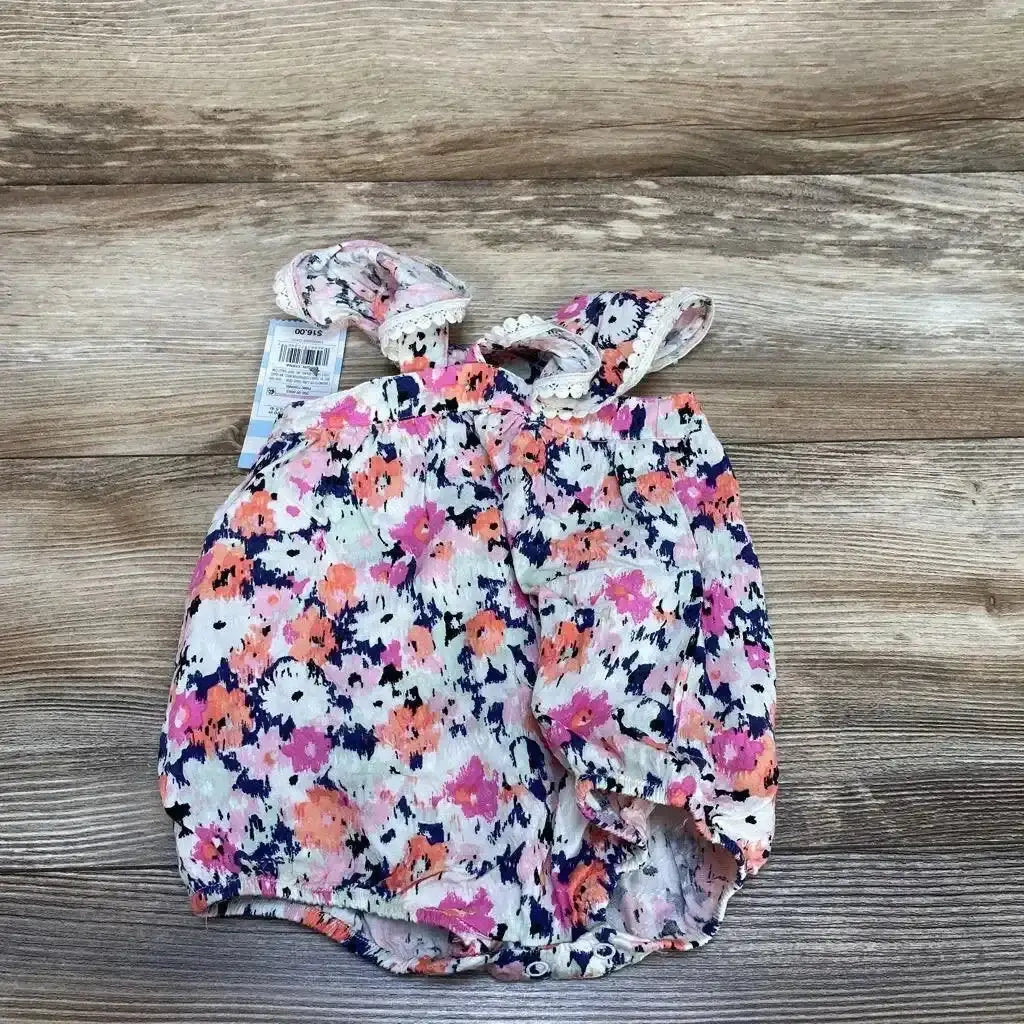 Top-down view of Cat and Jack newborn pink floral romper showcasing flutter sleeves and snap-button crotch on wood background