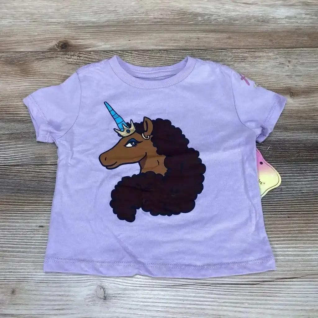 Flat lay of purple 12-month toddler t-shirt with afro-unicorn graphic, blue horn and crown, on wood background
