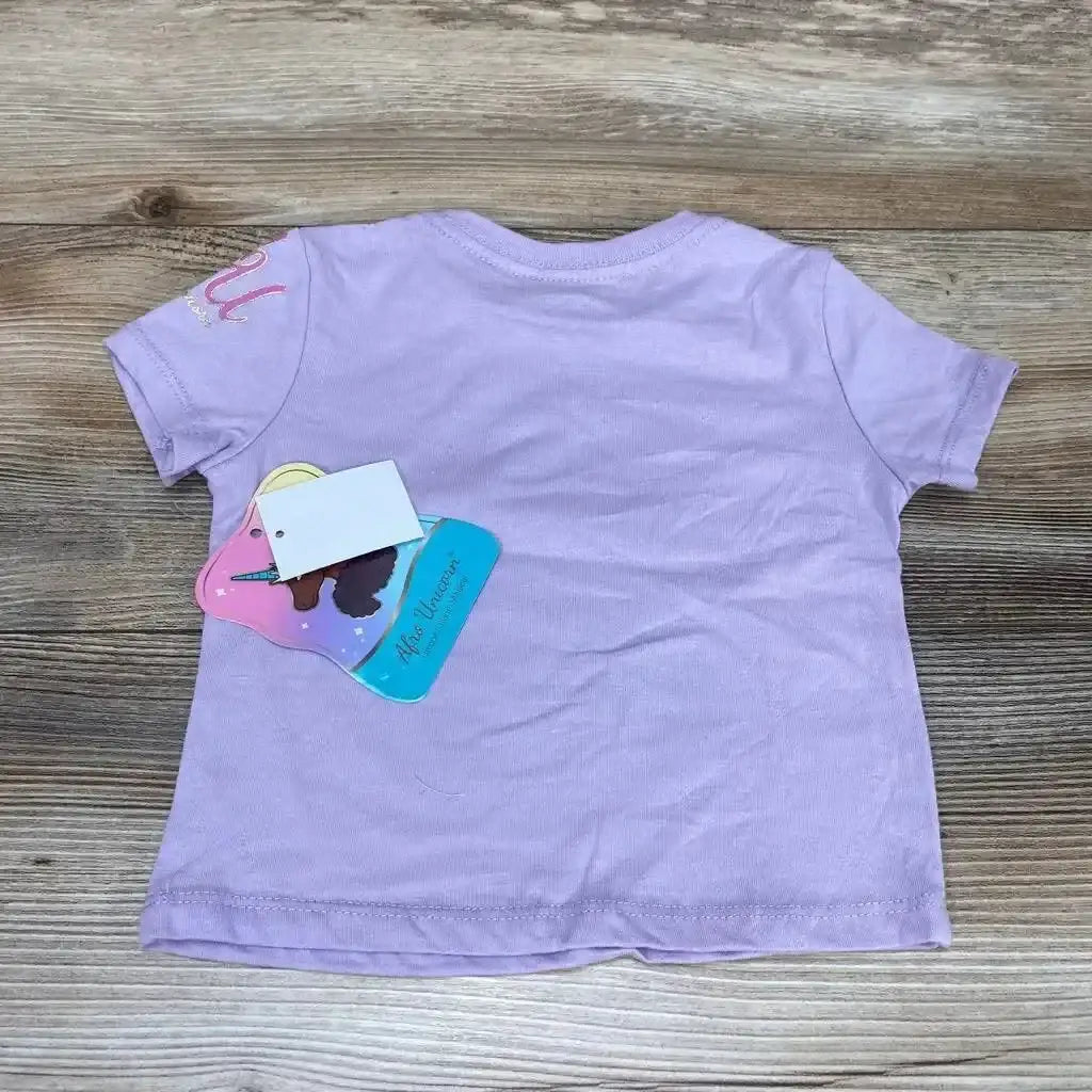 Back view of purple toddler short-sleeve Afro Unicorn shirt (12 months) with attached hang tag on wood background