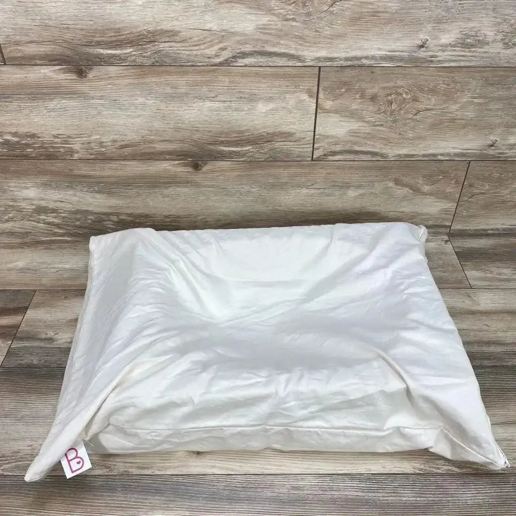 Three-quarter view of Belly Baby Breast pregnancy pillow showcasing soft white cushion with pink B logo tag on wood plank floor