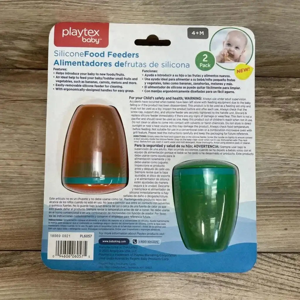 Back of Playtex 2 Pack Silicone Food Feeders 4m+ packaging showing orange and green feeders with instructions on wood floor
