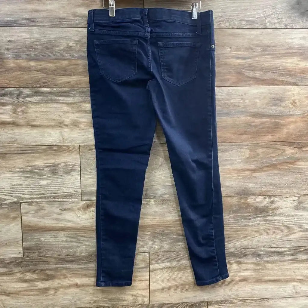 Back view of Isabel Maternity Side Panel Jeggings size XS in dark wash denim showcasing skinny leg fit and back pockets clipped to hangers on wood plank floor