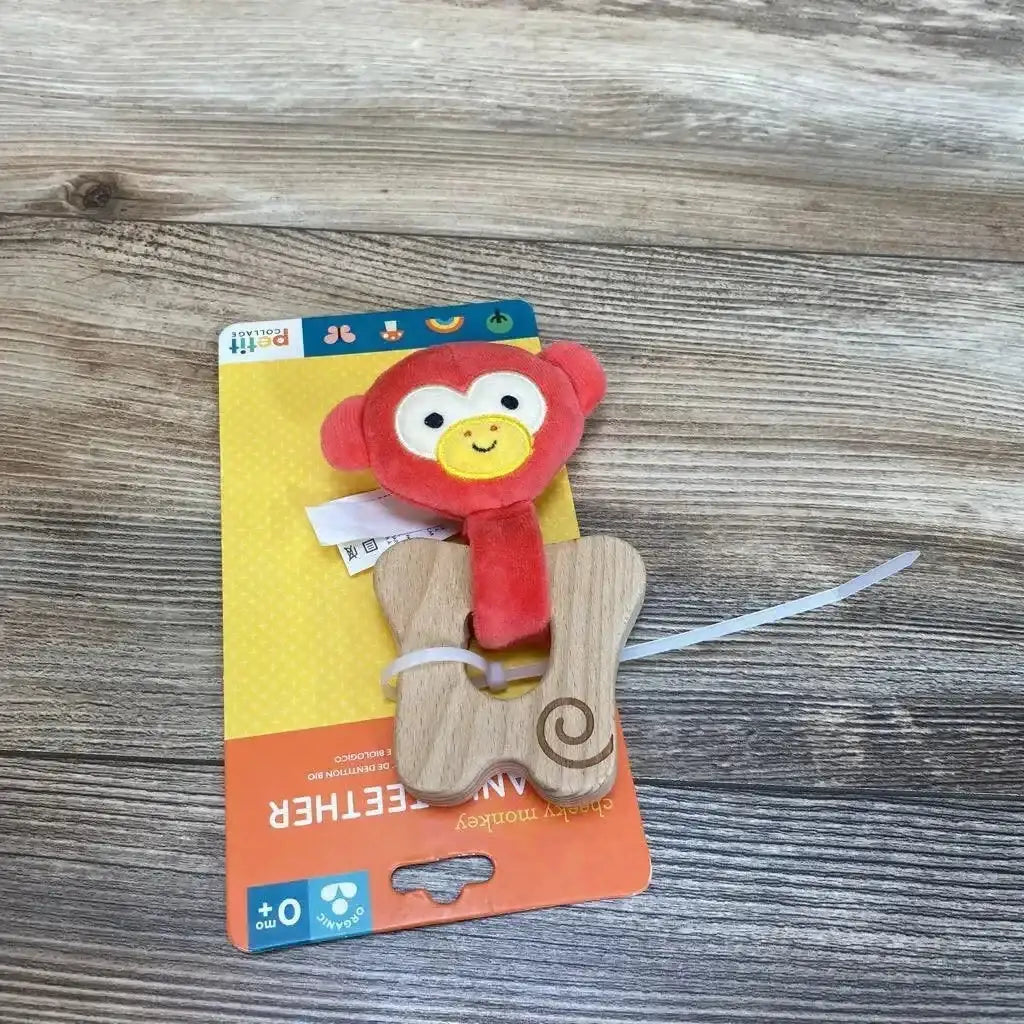 Top-down view of Petit Collage Cheeky Monkey organic teether with red plush monkey head attached to butterfly-shaped wooden teether on wood surface