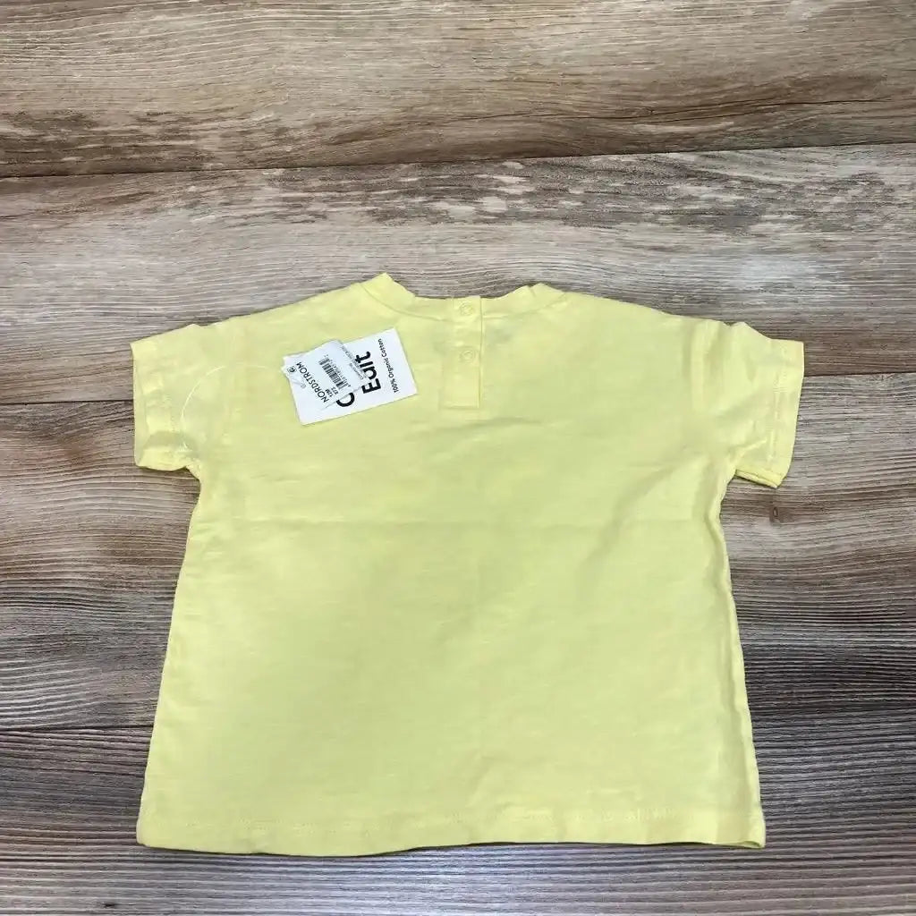 Back view of yellow organic baby short-sleeve t-shirt (12m) showing two back neckline snaps and tag on wood background