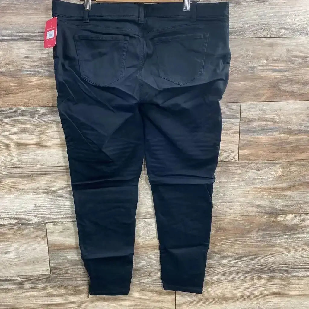 Back view of Isabel Maternity utility jeggings in black showcasing back pockets and hangtag on wood plank floor