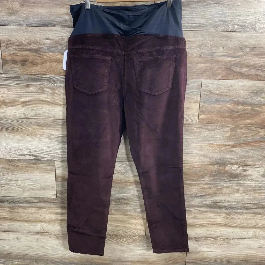Back view of burgundy Isabel maternity skinny jeans with crossover elastic belly panel and back pockets on wood floor