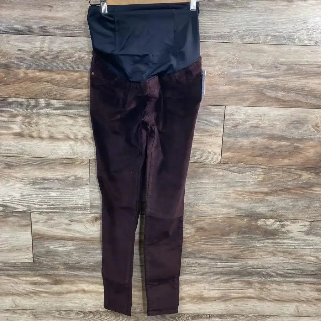 Front of Isabel maternity crossover-panel skinny jeans in burgundy (size 00) showing black belly panel on wood floor