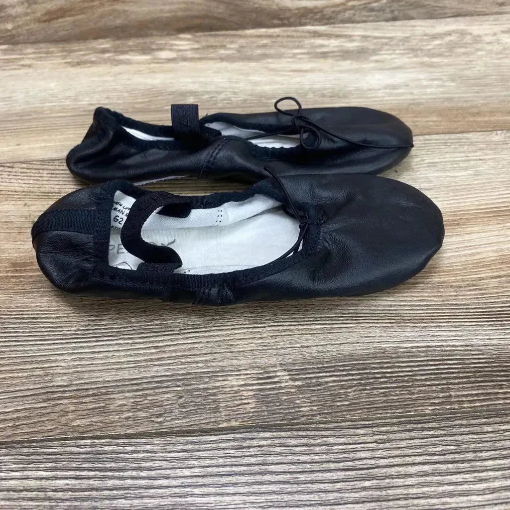 Top-down view of Capezio Daisy 205 ballet shoes showcasing elastic strap, drawstring front and soft black leather upper on wood floor