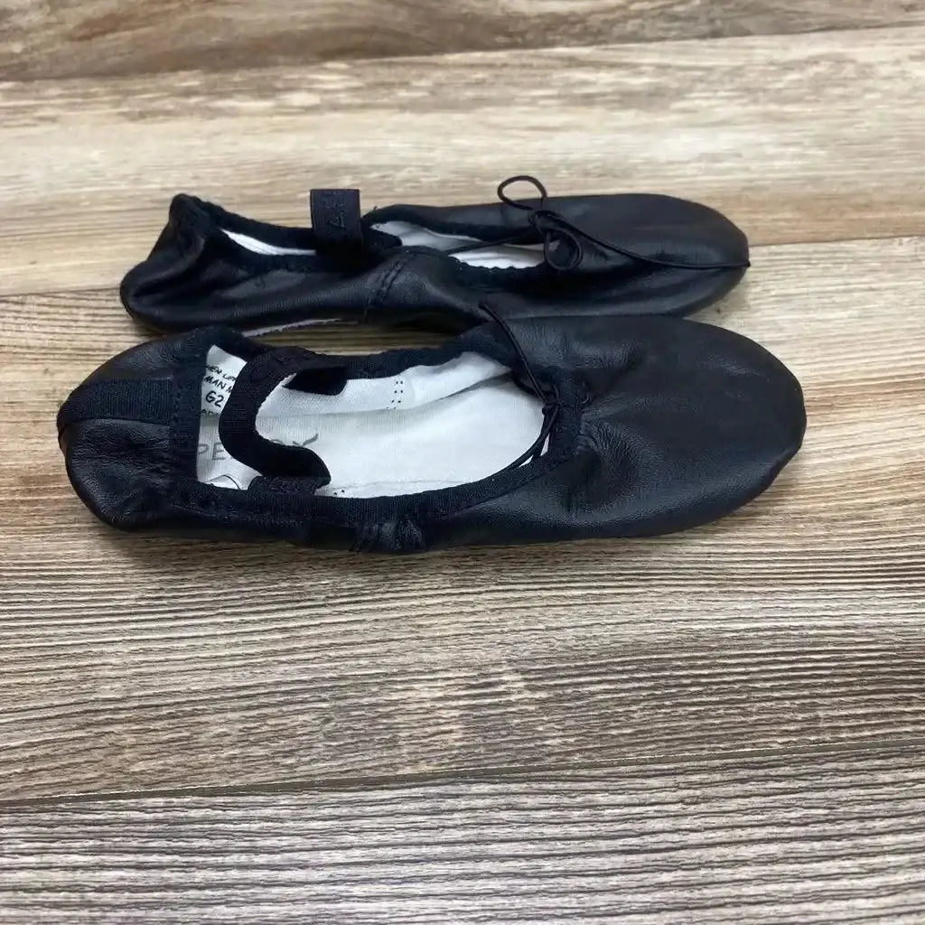 Top-down view of Capezio Daisy 205 ballet shoes showcasing elastic strap, drawstring front and soft black leather upper on wood floor