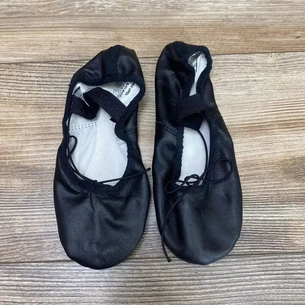 Top view of Capezio Daisy 205 black leather ballet shoes showing elastic strap, drawstring, and light wear on wood floor background