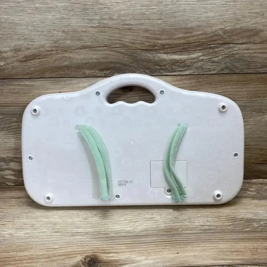 Back view of white B. Toys Musical Party Dance Pad showcasing carry handle, battery compartment and two green fabric straps on wood background