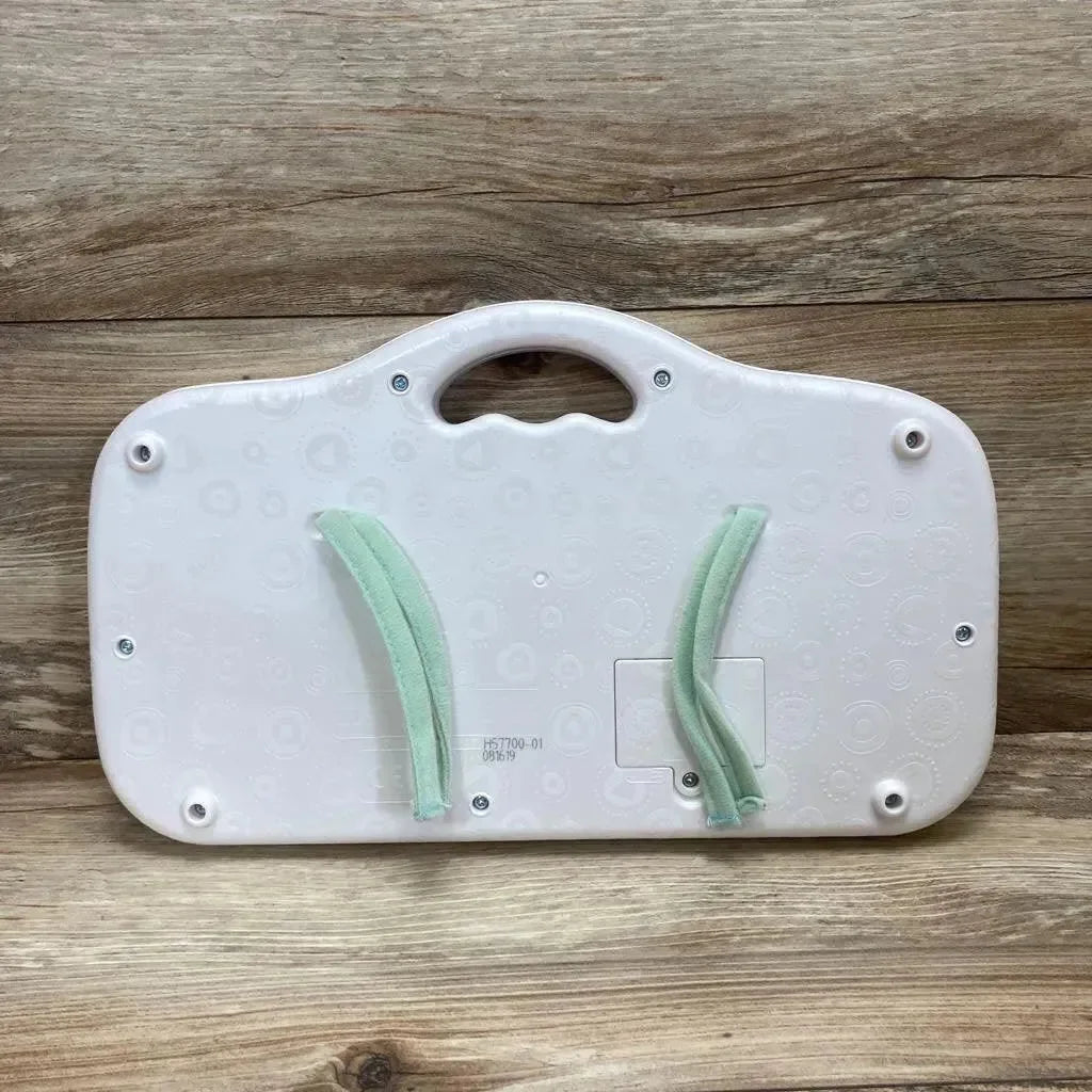 Back view of white B. Toys Musical Party Dance Pad showcasing carry handle, battery compartment and two green fabric straps on wood background