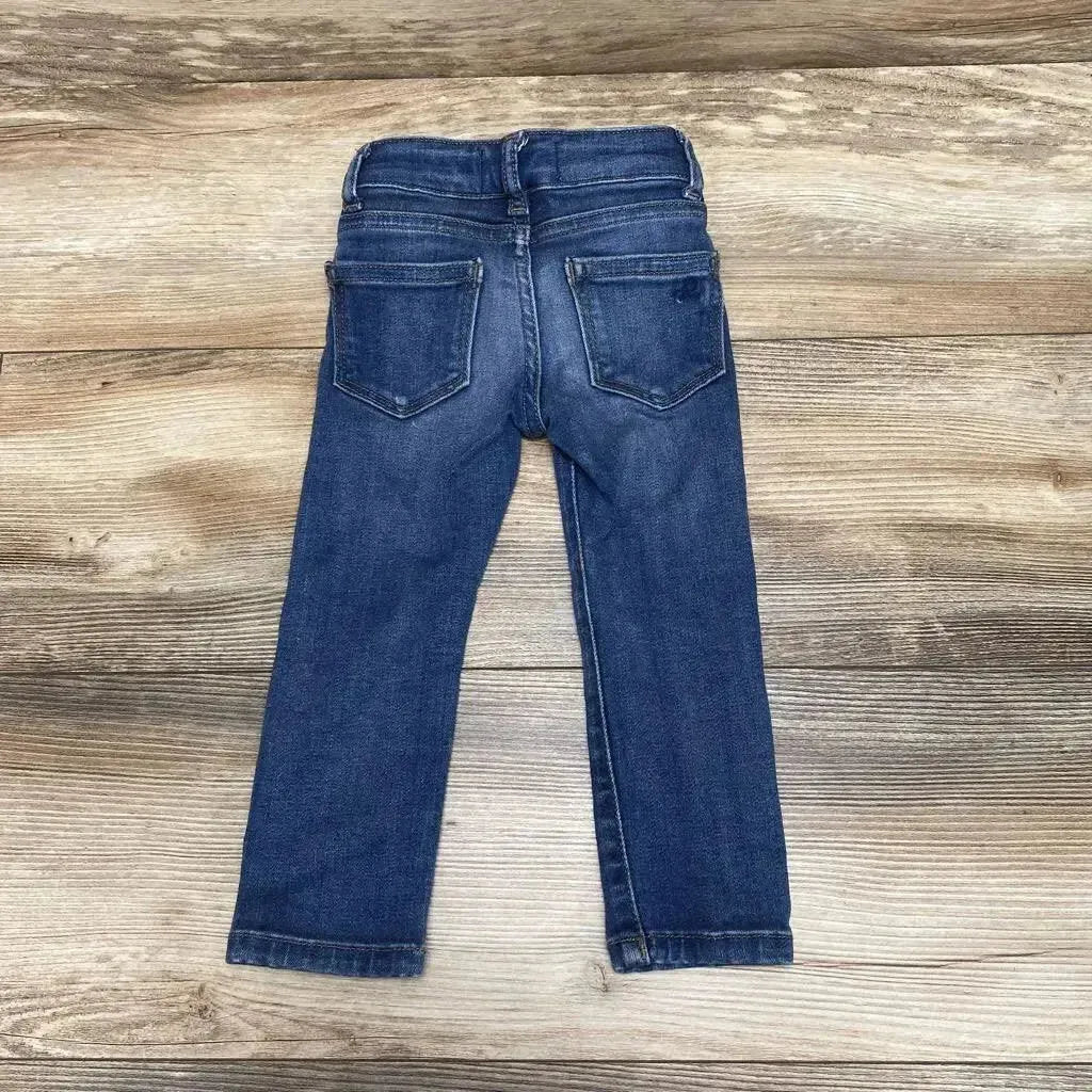 Back view of DL 1961 Chloe toddler skinny jeans in blue, showing rear pockets and slim legs on a light wood floor